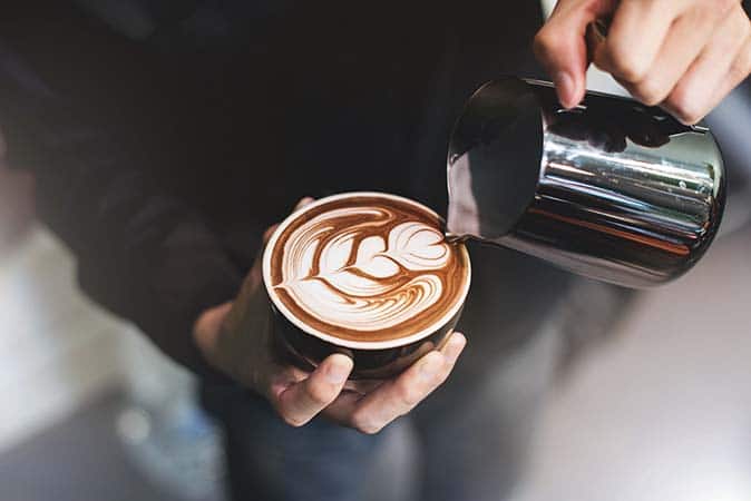 Barista crea un disegno con il latte in una tazza di caffè