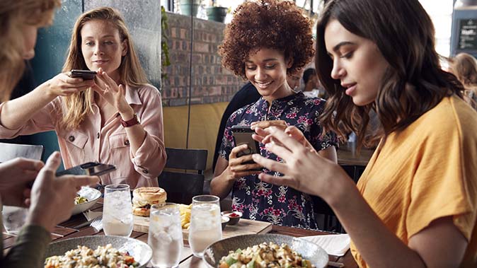 Un gruppo di ragazze fotografa i propri piatti in un ristorante