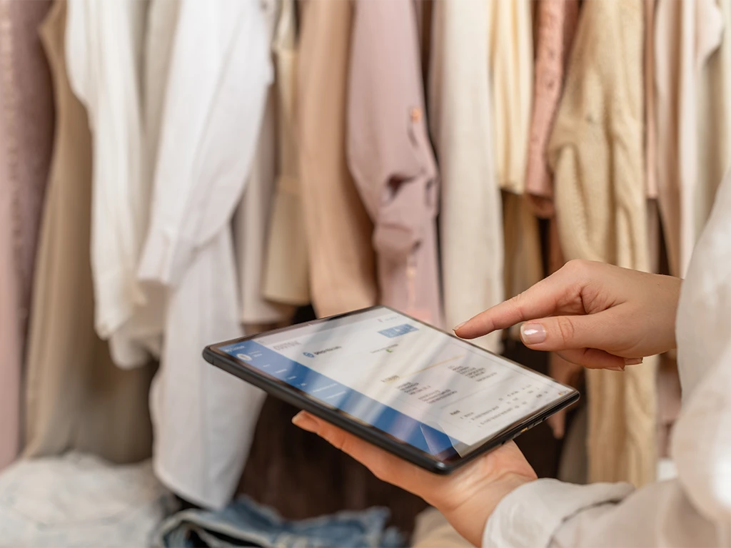 Una persona utilizza un tablet per consultare le fatture elettroniche emesse, all'interno di un negozio di abbigliamento